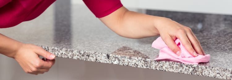 closeup young woman cleaning granite countertop