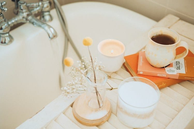 bath tray with candle, book, flowers and coffee