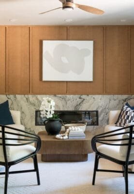 Living room fireplace surround in White Camouflage honed marble connecting to open kitchen design.